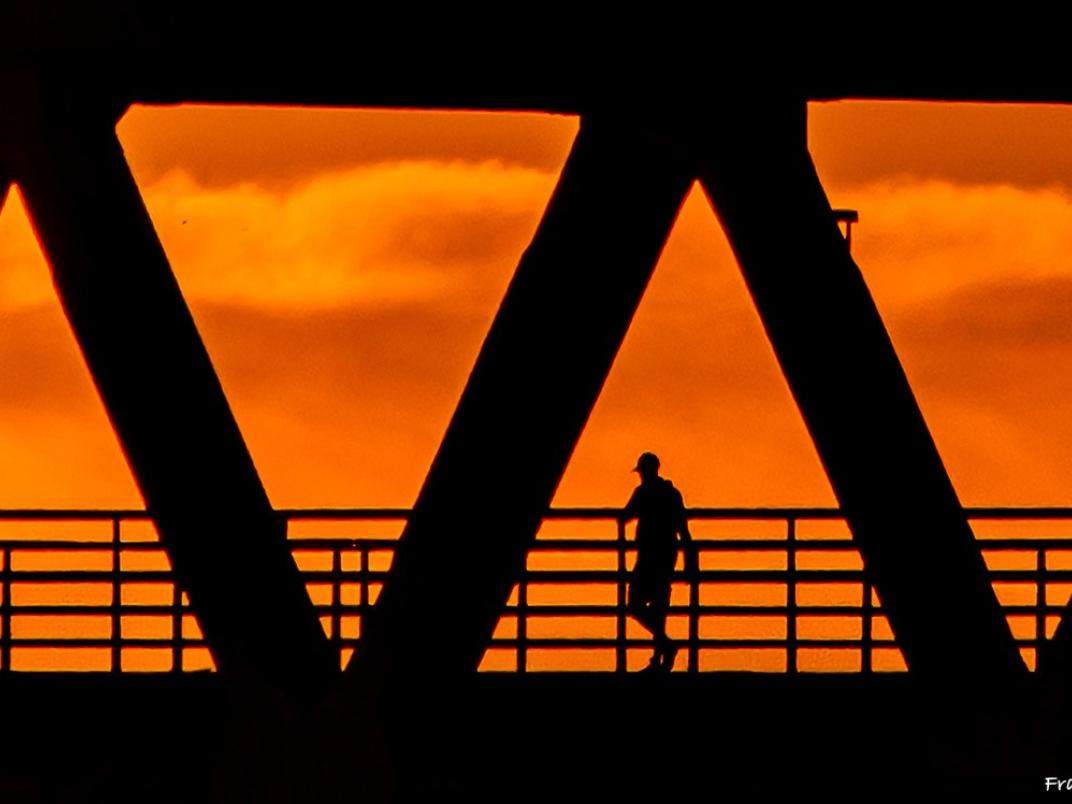 Man wandelt 's avonds over brug