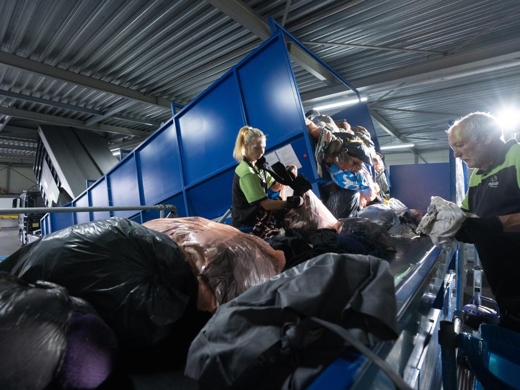 Mensen bij textielcontainer